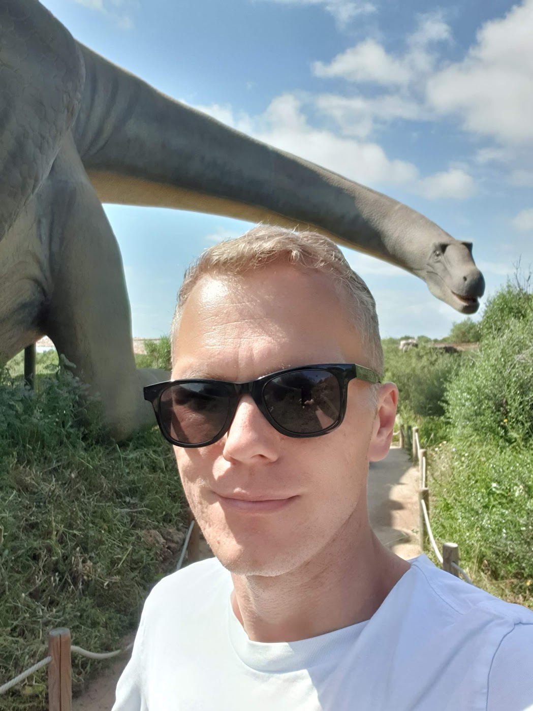 Tobias Zander, Portrait mit Sonnenbrille und einem Brachiosaurus-Modell im Hintergrund